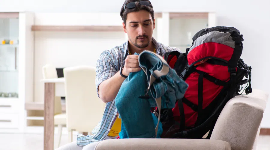 A man packing a backpacking pack with clothes for a mission trip.