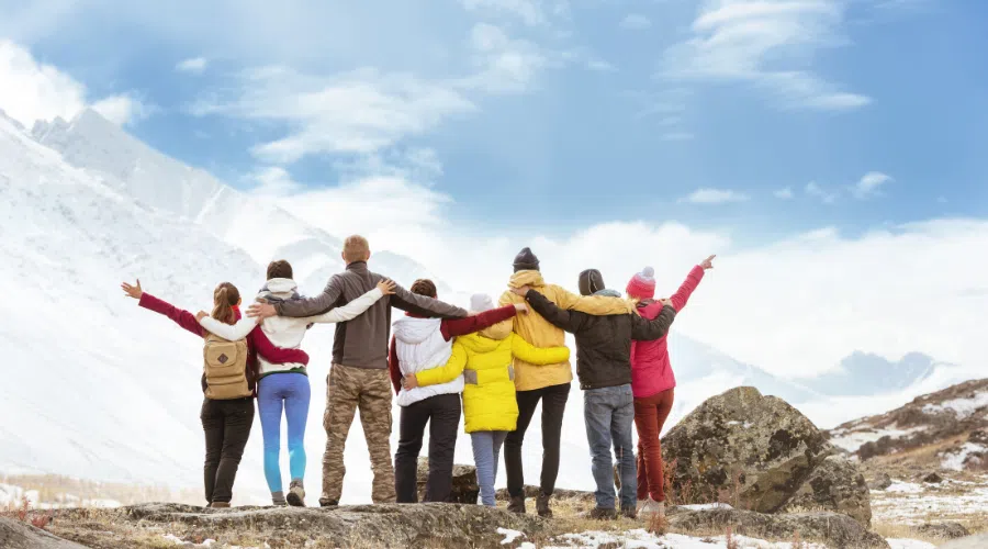 group of eight people photographed from the back while they overlook a glacier and celebrating their hike. Concept image for educational tours