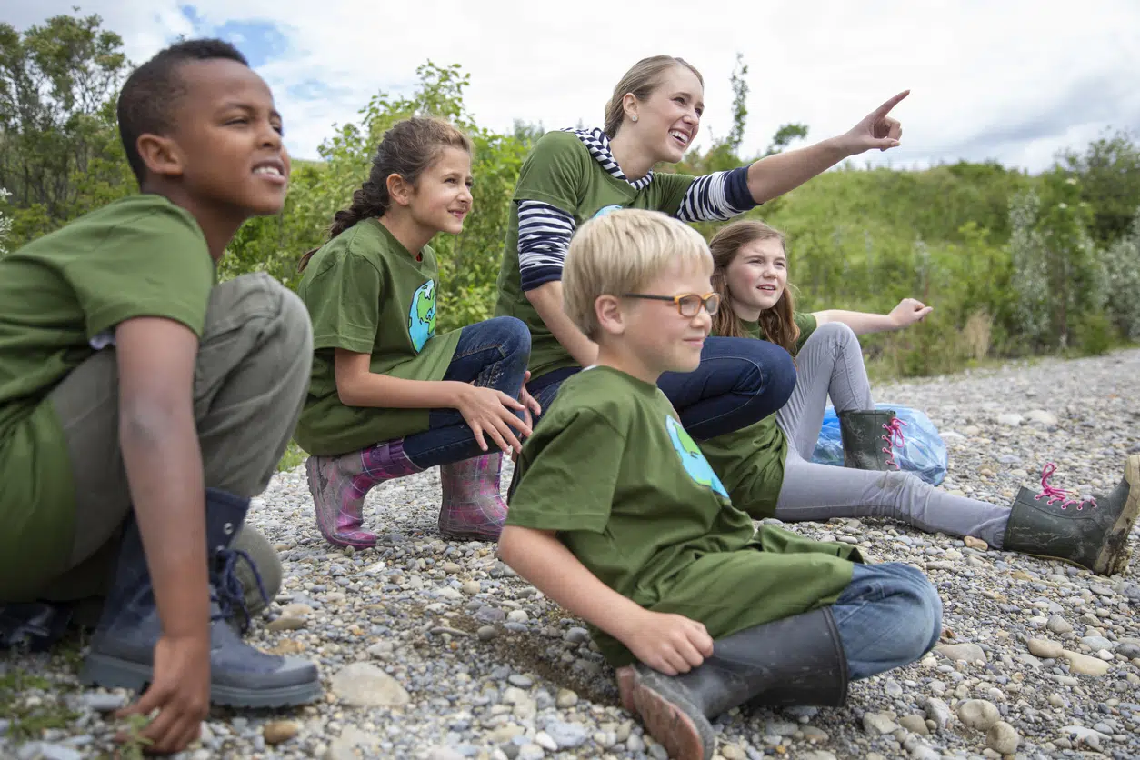 picture of a group of kids at summer camp with a camp counselor pointing into the distance