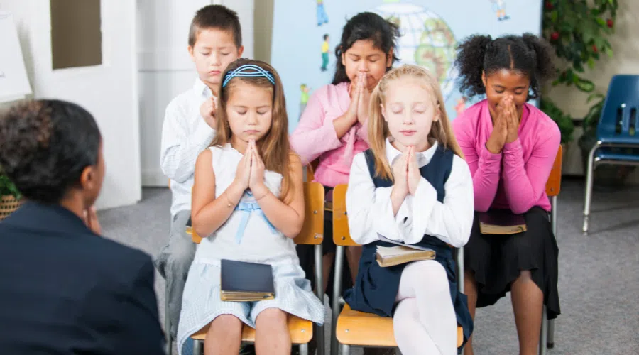 A group of girls praying while all sitting together with a guide and leader.
