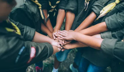 Six boy scouts putting their hands together in a circle