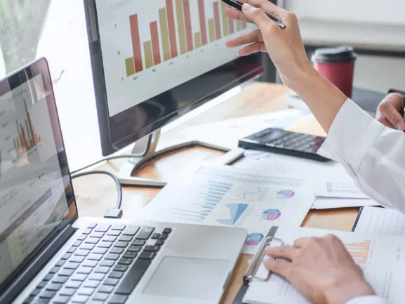 modern office a laptop open paper reports on the desk a screen with a graph