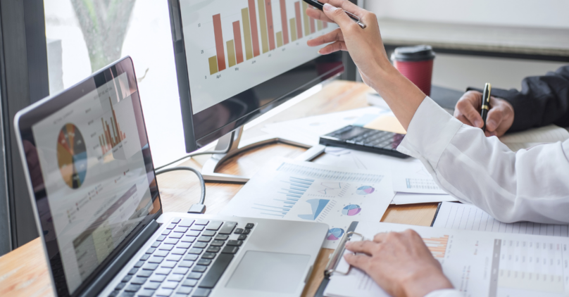 modern office a laptop open paper reports on the desk a screen with a graph