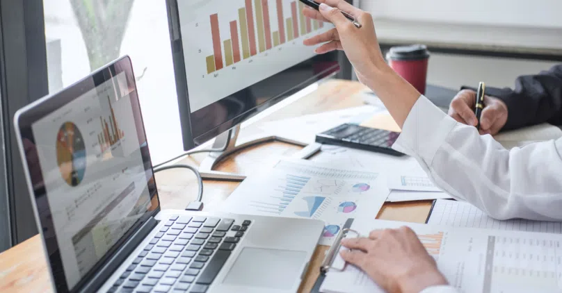 modern office a laptop open paper reports on the desk a screen with a graph